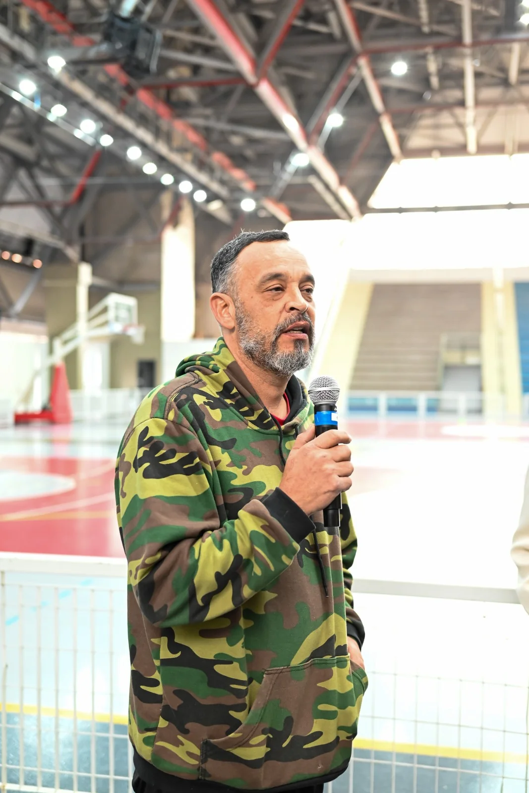 Apresentador segurando microfone durante evento em quadra esportiva